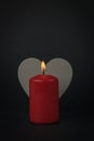 A candle with a lit wick on the background of a gray wooden heart Royalty Free Stock Photo