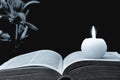 Candle, opened book and flowers on black background Royalty Free Stock Photo