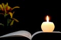 Candle, opened book and flowers isolated on black Royalty Free Stock Photo