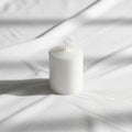 Candle is placed on a white fabric surface with visible textures Royalty Free Stock Photo