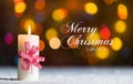 Candle with red bow, in snow, with defocussed fairy lights, bokeh in the background, Festive Christmas background