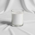 Candle with a single wick centered on a draped white fabric background. Royalty Free Stock Photo