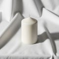 Candle with a smooth surface is positioned on a draped, white Royalty Free Stock Photo