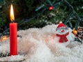 Candle and a sn on decorative snow under a Christmas tree Royalty Free Stock Photo