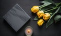 a candle and some yellow tulips on a table