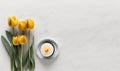 a candle and some yellow tulips on a white table