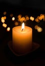 A candle on a stand burns in the dark. Royalty Free Stock Photo