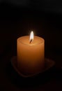 A candle on a stand burns in the dark. Royalty Free Stock Photo