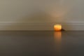 Candle standing on the floor against the wall