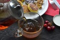 a candle stands next to a plate with cheese pancakes and tea is poured into a cup