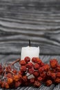 Candle stub on brushed pine boards. Nearby is a dried rowan bunch