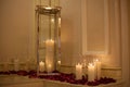 Candle surrounded by red rose petals with dreamy reflection