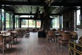 Candle on table in bright restaurant interior with wooden chair and plant. Real photo.