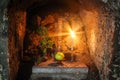 Prayer alter: candle, food offering and plant inside a Buddhist cave in Japan