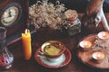 Candle wax poured into a red and gold vintage teacup as a divination form with a yellow burning candle standing next to it