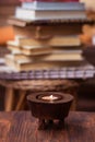 Candle on wooden table with books in background Royalty Free Stock Photo