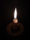 Burning candle in a candlestick on a black background Royalty Free Stock Photo