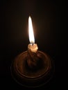 Burning candle in a candlestick on a black background Royalty Free Stock Photo