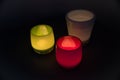 The candlelight from three lanterns in red, green and white glow in the darkness