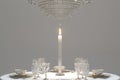 A candlelit dinner setting with an elegant crystal chandelier hanging above a round table.