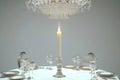 A candlelit dinner setting with an elegant crystal chandelier hanging above a round table.