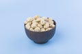Candlenut spice in wooden bowl on blue background