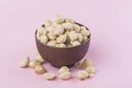 Candlenut spice in wooden bowl on pink background