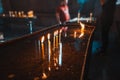 Candles are burning in a medieval dark Catholic church and rays of light make their way through a narrow window. The Royalty Free Stock Photo