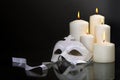Candles and carnival mask over black background