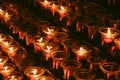 Candles in a dark Catholic Cathedral. Prayer, incense and Christian Faith. Row of small lit votive candles in red glass Royalty Free Stock Photo