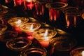 Candles in a dark Catholic Cathedral. Prayer, incense and Christian Faith. Row of small lit votive candles in red glass Royalty Free Stock Photo