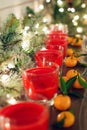 Candles in glass candlesticks stand on a shelf with a luminous garland and tangerines