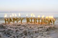 Candles Gold Letters Happy Birthday Burning on Background of Blurry Sea Waves