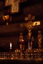 Candles on stand with candlesticks burning on altar in front of crucifixion of Jesus, holy virgin Mary and apostle John.