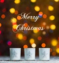 Candles standing in snow with defocussed fairy lights, colourful bokeh in the background, Festive Christmas background Royalty Free Stock Photo