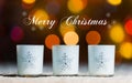 Candles standing in snow with defocussed fairy lights, gold bokeh in the background, Festive Christmas background Royalty Free Stock Photo