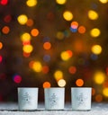 Candles standing in snow with defocussed fairy lights, orange or golden bokeh in the background Royalty Free Stock Photo