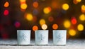 Candles standing in snow with defocussed fairy lights, orange or golden bokeh in the background Royalty Free Stock Photo