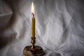 Candlestick with a burning candle on the background of rumpled linen fabric. Dark vignette Royalty Free Stock Photo