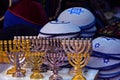 Candlesticks of the menorah are gold and silver. Knitted multi colored kipa are sold in the market in Jerusalem