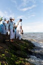 Candomble people stand on top of the rocks at Rio Vermelho beach, offering gifts to Yemanja