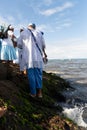 Candomble people stand on top of the rocks at Rio Vermelho beach, offering gifts to Yemanja