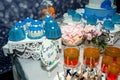 Candy bar and desserts for children`s birthday party: blue and white cakes, pink marshmallows, macarons.