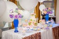 Candy bar on golden wedding party with a lot of different candies, cupcakes, souffle and cakes. Decorated in brown and purple colo Royalty Free Stock Photo