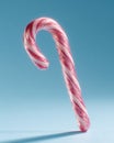 Candy Cane-Festive candy cane with red stripes against a light blue background, casting shadow Royalty Free Stock Photo