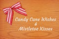 Candy cane wishes and mistletoe kisses greeting with Christmas red and white candy cane bow