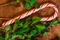 Candy canes with mint leaves on a wooden background