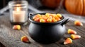 Candy corn in a cauldron with candle on wooden table, Halloween vibes. Royalty Free Stock Photo