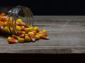 Candy Corn spilling out of a glass jar on a wood table Royalty Free Stock Photo