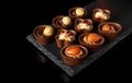 Candy with cream and nuts on a slate board. Assorted chocolate on black isolated background. Idea for dessert in restaurant Royalty Free Stock Photo